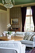 Pale sofa set and round wooden table in traditional living room