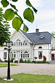 View past traditional street lamp in garden to elegant, white house with conservatory extension