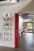 Wall plates with anatomical motifs next to open doorway with red sliding door and view into home office