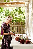 Frau mit Protea, auf Terrasse mit Spülbecken, vor Wohnhaus