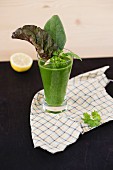 A green smoothie garnished with spinach and chard leaves
