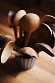 Several vintage wooden spoons in pot on wooden surface