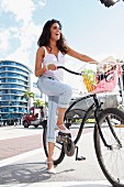 A young, dark-haired woman wearing summery clothes with a bike in the city