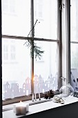 Paper city skyline stuck to window, candles and pine cones on windowsill