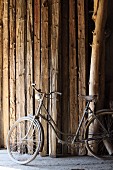 Vintage Fahrrad vor dem Vorrat an Holzstämmen in der Scheune einer Wildholz-Schreinerei