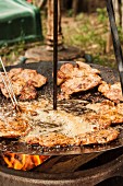 Slices of meat being fried in oil in a rustic pan