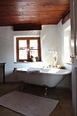 Blick durch offene Tür auf freistehende Badewanne vor Fenster in renoviertem Bad