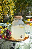 Home-made lemonade in vintage jar on tray next to colourful bouquet of wildflowers