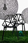 Spherical pendant lamps (Random Light) made from fibreglass mesh and designer chairs with hexagonal struts on lawn