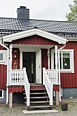 Traditionelles Schwedenhaus mit Veranda, Treppenabgang und geöffneter Eingangstür