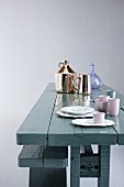 China, glass and shiny chrome tableware on rustic wooden table painted grey