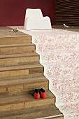 Floral fabric runner laid on wooden steps and modern shell chair majestically arranged as throne flanked by silver bird figurines