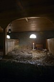 Bed made up with blanket and candlestick in hay loft