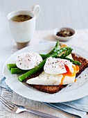 A slice of bread topped with haddock, poached egg and asparagus