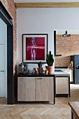 Open-plan, modern kitchen with wooden doors, black frames and modern artwork above collection of cacti