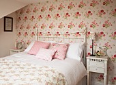 Double bed with white, metal, lattice frame in romantic bedroom with floral wallpaper