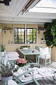 Holzliege und Sitzplatz in pastellgelber romantischer Loggia mit Sprossenfenster in Holzwand