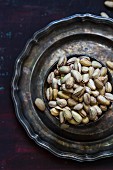 A bowl of pistachios on a pewter plate