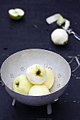 White Transparent apples, partially peeled, in a colander