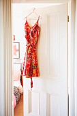 Colourful summer dress hanging on half-open bedroom door