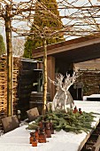 Snow-covered table decorated with fir branches on terrace