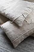 Vintage-style cushions with ecru linen covers on grey woven carpet