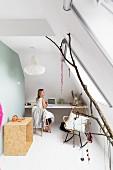 Room with sloping ceiling, integrated desk and jewellery hanging from branch