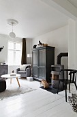Wohnzimmerecke in weiss grauen Farbtönen, Couchtisch mit weisser Platte, dunkelgrau lackierter Schrank auf weißem Dielenboden