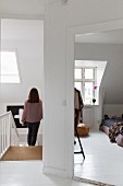 Woman walking down bright staircase and view into bedroom with sloping ceiling