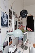 Desk with flatscreen monitor and retro table lamp below photo collage on wall