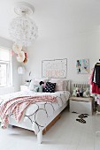 Bed linen with graphic pattern and scatter cushions on feminine bed and spherical pendant lamp in romantic bedroom
