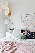 Gemusterte Kissen und gestreifte rosafarbene Tagesdecke auf Doppelbett in romantischem Schlazfimmer