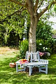 Schattiger Gartenplatz unter Baum mit selbstgebauter Baumbank, hellgrau und weiß lackiert