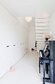 Narrow foyer with white fitted cupboards, upright piano and staircase with white treads