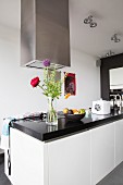 Free-standing counter with black stone counter, white fronts and stainless steel extractor hood