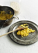 Risotto alla milanese on a plate with a wooden spoon and in a pot