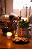 Stillleben mit Kerzenlichtstimmung, Kräutertöpfe und Knoblauchzehen auf Schale zwischen brennenden Kerzen