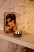 Zündholzschachtel mit Frauneportrait und Teelicht mit kronenförmigen Messingbehälter vor Kerzen