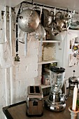 Retro Kleingeräte aus verchromtem Metall, oberhalb an Stange aufgehängtes Vintage Kochgeschirr