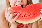 Mädchen beisst in eine Wassermelonenscheibe