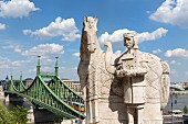 A statue of St Stephen in front of the Cave Church with a view of the Chain Bridge, Budapest, Hungary