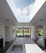 Offener Wohnraum mit Oberlicht in Decke über Kücheninsel, im Hintergrund Essplatz in zeitgenössischem Wohnhaus