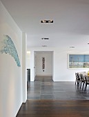 Grosszügiger, minimalistischer Wohnraum mit teilweise sichtbarem Essplatz in zeitgenössischem Wohnhaus