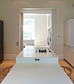 Esstisch und Küchentheke Kombination in Weiß, im Hintergrund Durchgang mit Blick ins Wohnzimmer