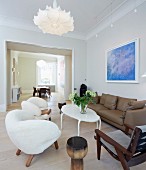 Wohnzimmer mit extravaganten, Sesseln in Weiß und braunes Ledersofa um Couchtisch, im Hintergrund breiter Durchgang und Blick auf Essplatz
