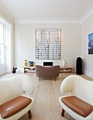 Extravagante Sessel mit weißem, fellartigem Bezug und Lederkissen im Wohnzimmer
