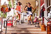 Zwei weibliche Teenager springen vor Freude auf einem Bürgersteig in der Stadt