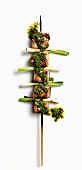 A pork belly skewer with spring onions and salsa verde