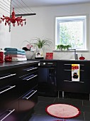 Modern laundry room with black base units, stainless steel strip handles, round rug and black tiled floor