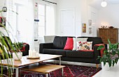 Nest of low coffee tables and black couch in open-plan interior